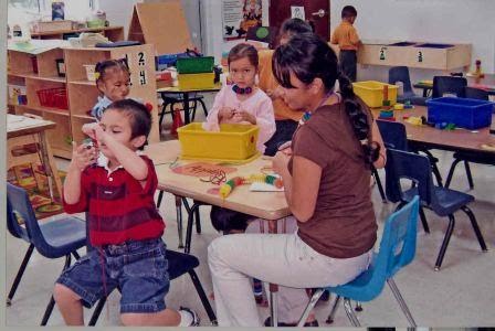 A parent with her child sitting at a table in the classroom