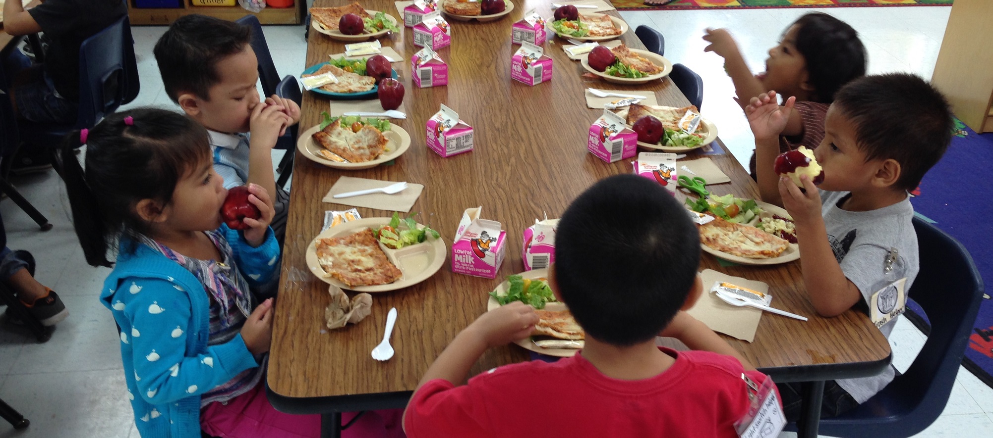Kids eating lunch together in a cafeteria. 